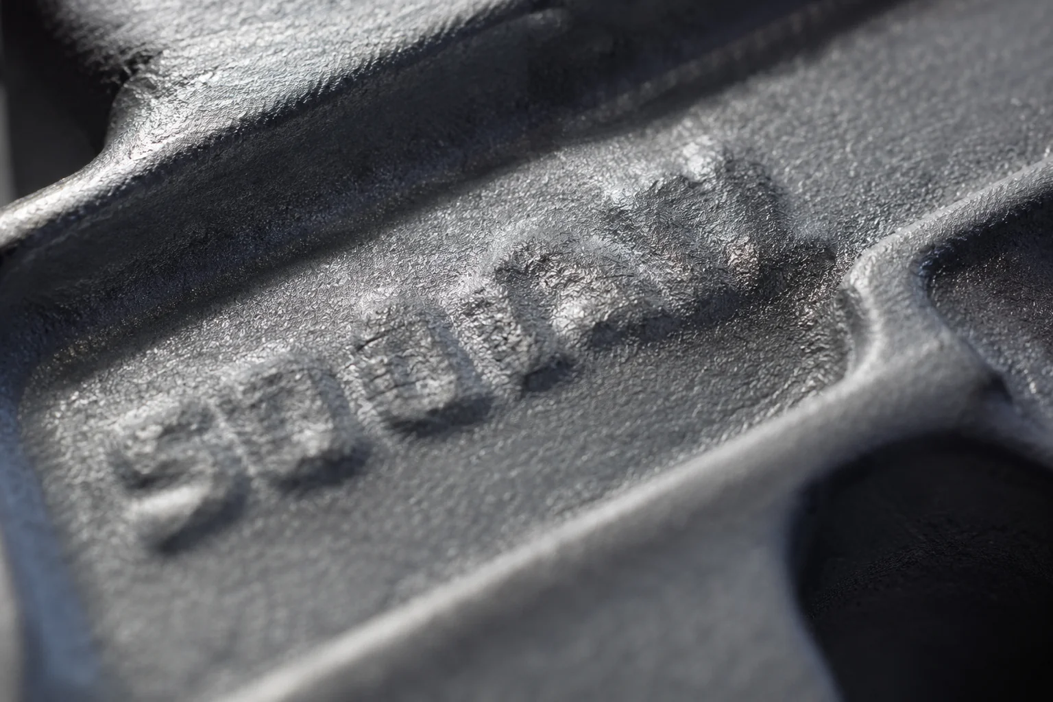 A cast marking stamped into the surface of an unbranded metal part